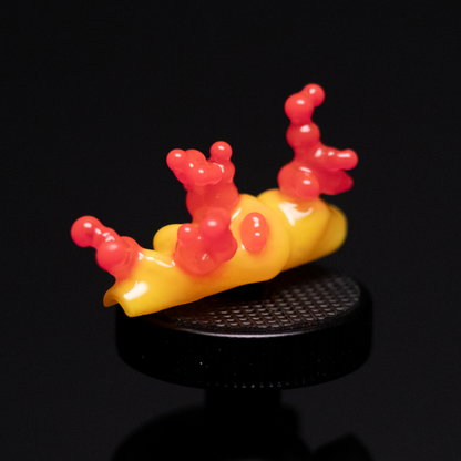 A vibrant yellow and red handmade press-on nail design, featuring red bubbly protrusions on a yellow base, inspired by nudibranch shapes.