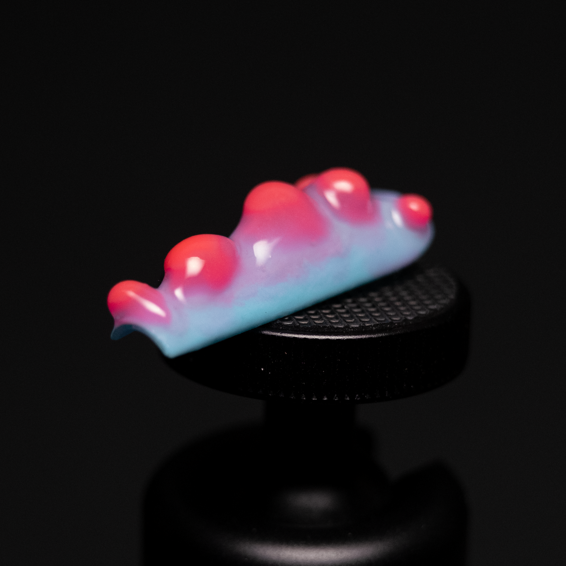 A handmade press-on nail inspired by lava lamps and ocean creatures like nudibranchs, featuring a soft blue base with glowing pink and red rounded shapes.