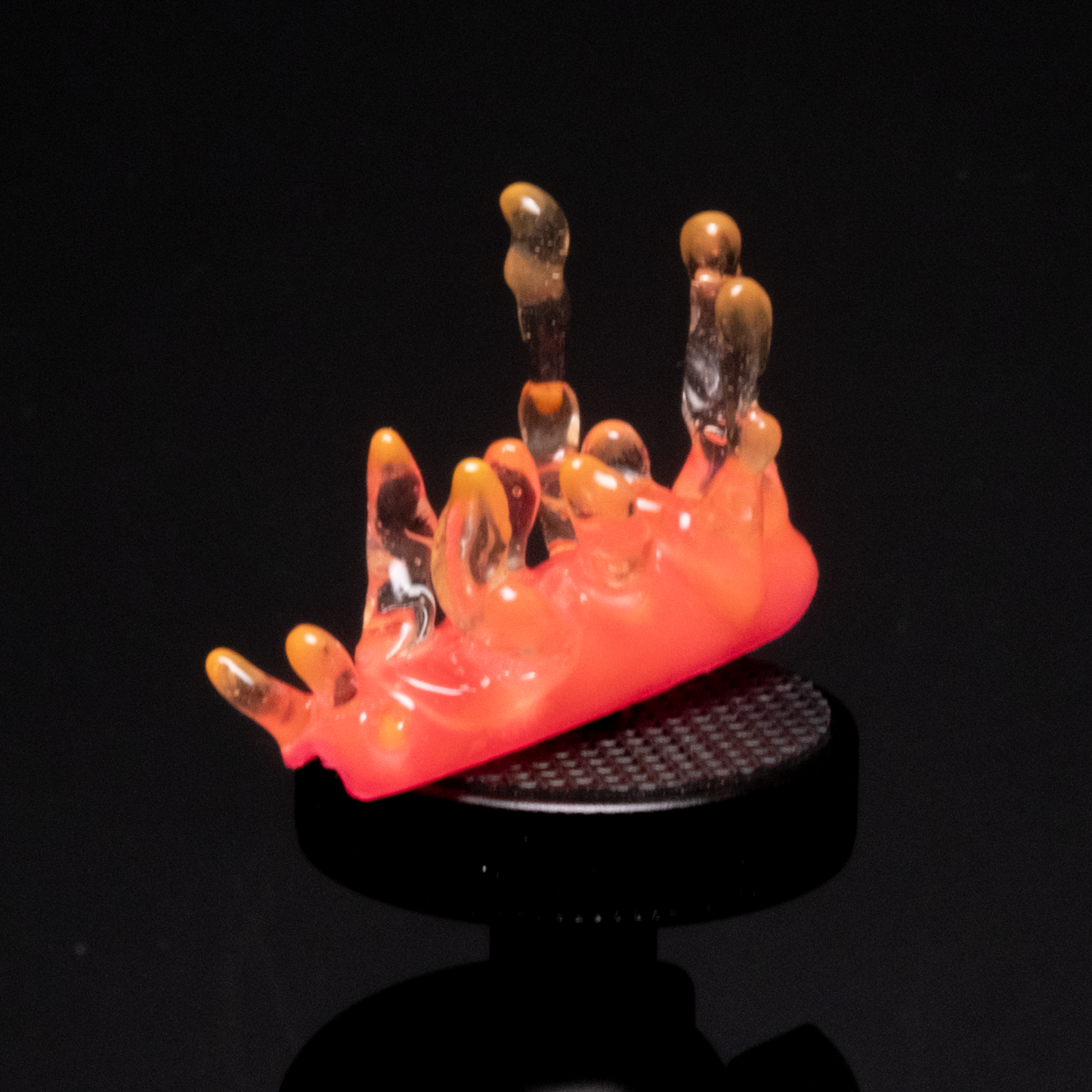 A close-up of a handmade neon coral-like press-on nail featuring bright orange, pink, and clear spikes, resembling underwater sea creatures.