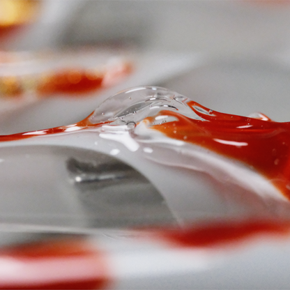 A close-up of a koi-inspired press-on nail, showcasing intricate red and white swirls with a glossy 3D finish, symbolizing good luck and elegance.